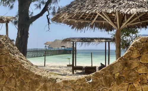 a beach with an umbrella and the ocean at Kiwengwa Bungalow Boutique Resort in Kiwengwa