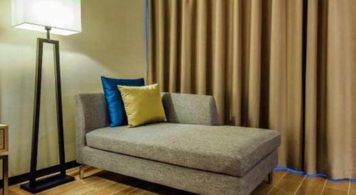 a couch with a yellow pillow and a lamp at Echarm Hotel Anshun High-speed Railway Station Jichang Road in Anshun
