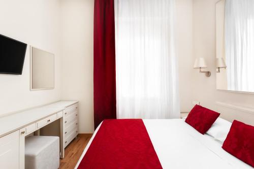 a bedroom with a white bed with red pillows at Best Western Hotel Nazionale in Sanremo