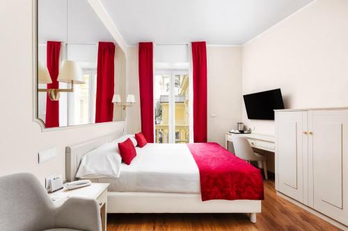 a bedroom with a bed with red curtains and a desk at Best Western Hotel Nazionale in Sanremo