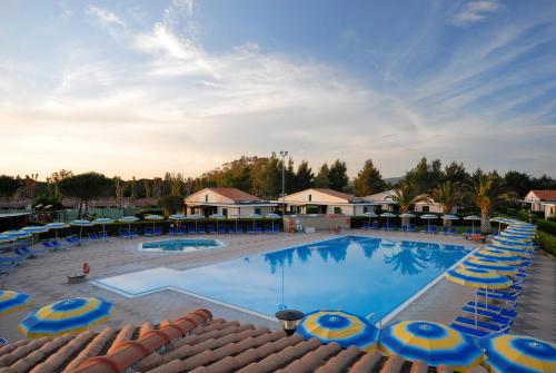 una grande piscina con ombrelloni blu e gialli di La Cecinella Apartments a Marina di Cecina