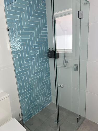 a bathroom with a shower with a blue and white pattern at Arno Bay Tourist Accommodation in Arno Bay