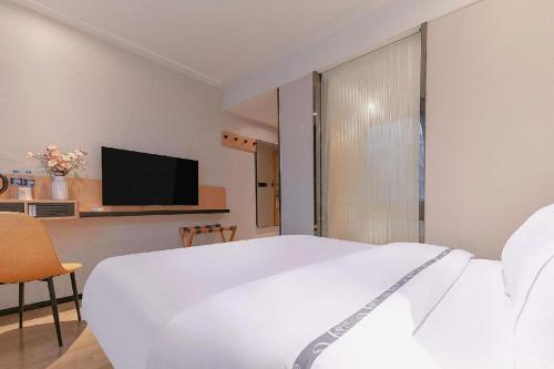 a bedroom with a white bed and a tv at City Comfort Inn Liuzhou High-speed Railway Station in Liuzhou