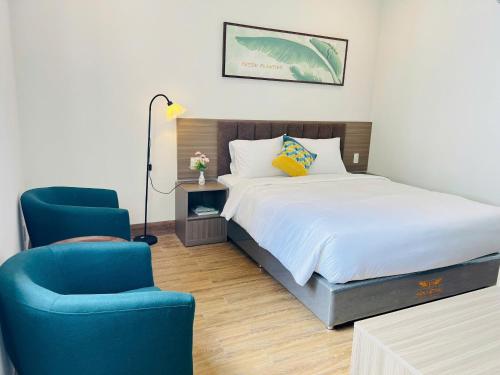 a bedroom with a bed and two blue chairs at Swan Boutique Hotel in Ho Chi Minh City