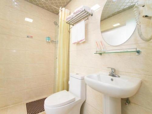 a bathroom with a toilet and a sink and a mirror at Shell Hotel Yangzhou Yangzijiang Bei Road Slender West Lake Scenic Area in Yangzhou