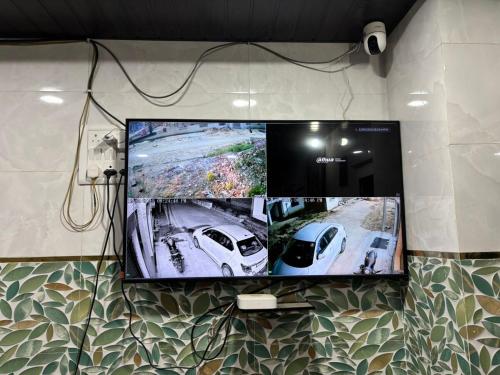 a tv on a wall with two pictures of two cars at Sarita's homestay in Ayodhya