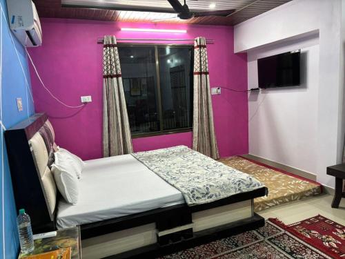 a bed in a room with a purple wall at Sarita's homestay in Ayodhya
