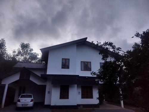 a white house with a car parked in front of it at Varietyvilla Homestay in Kattappana
