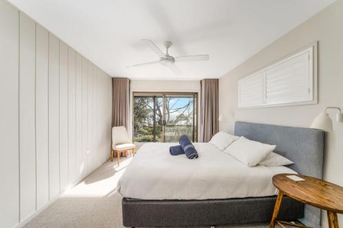 a bedroom with a bed and a table and a window at Chinamans at Hyams Beach in Hyams Beach