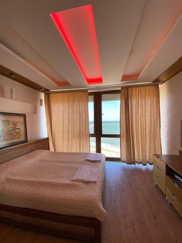 a bedroom with a large bed with a large window at Уютный дом на первой линии моря in Chornomorsk