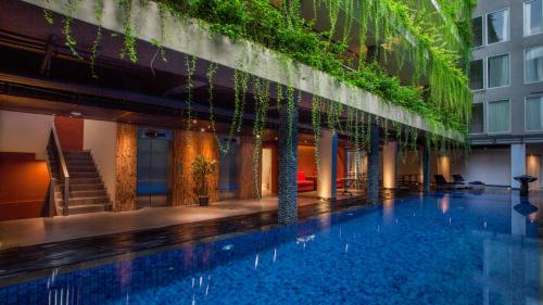 a hotel swimming pool with plants on the side of a building at Hotel Daun Bali Seminyak in Seminyak
