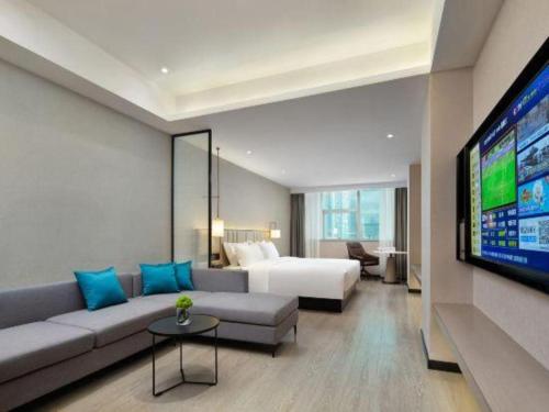 a living room with a couch and a bed and a tv at Borrman Hotel Golden Crown Liuzhou Wuxing Pedestrian Street in Liuzhou