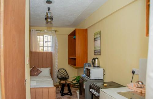 a small room with a kitchen with a bed in it at Stylish Mauve Studio with free WI-FI in Nanyuki