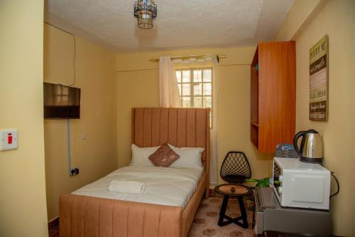 a small bedroom with a bed and a television at Stylish Mauve Studio with free WI-FI in Nanyuki