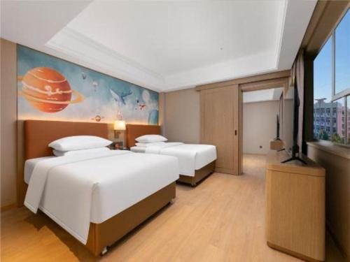a hotel room with two beds and a painting on the wall at Vienna Hotel Hubei Jinzhou Changjiang University in Caoshi