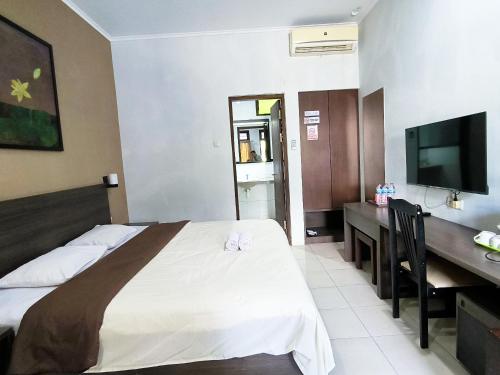 a bedroom with a bed and a desk and a television at Wisma Griyaku 1 in Purbolinggo