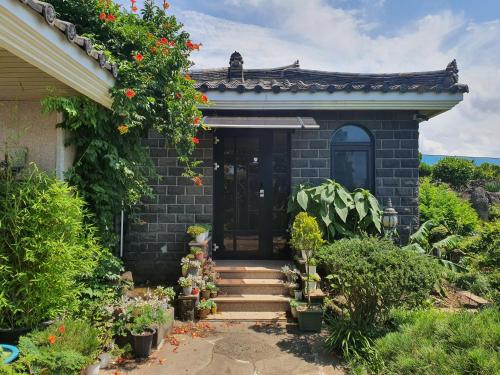 una casa de ladrillo con una puerta negra y flores en Samojeong, Jeju, en Jeju