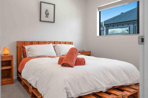 a bedroom with a bed with white sheets and a window at Cozy Retreat with Hot Tub in Christchurch
