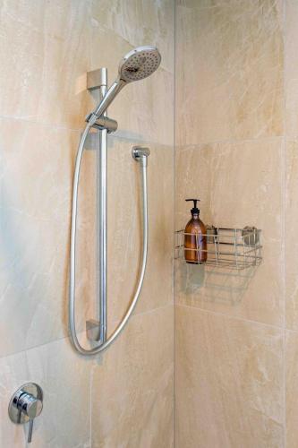 a shower with a shower head in a bathroom at Cozy Retreat with Hot Tub in Christchurch