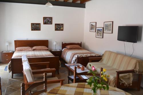 a bedroom with two beds and a couch and a tv at I Plateia in Kalopanayiotis