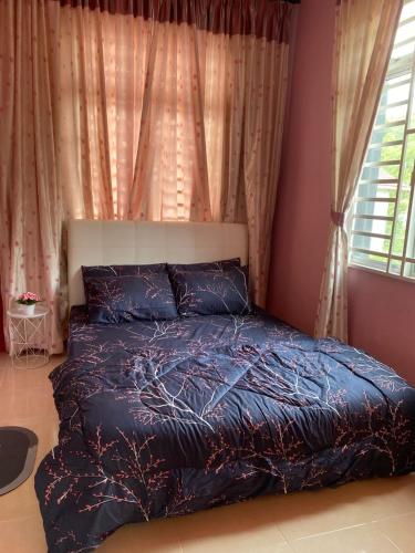 a bed with a blue comforter in a bedroom at The Deck Homestay & Event House in Jitra
