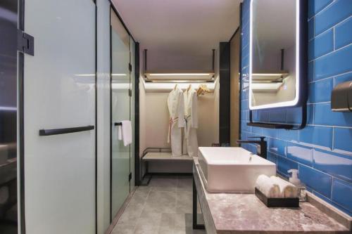 a bathroom with a white sink and a mirror at Echarm Hotel Nanjing Expo Center Olympic East Metro Station in Nanjing
