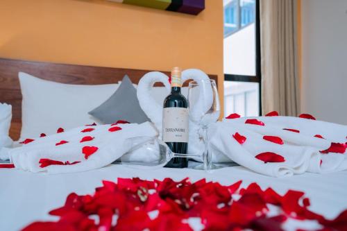 a bottle of wine sitting on a bed with red roses at Home Chic Hotel in Phnom Penh