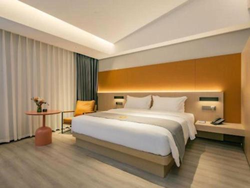 a hotel room with a large bed and a table at Airfeel Hotel in Ziyang