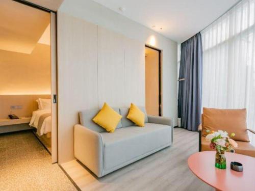 a living room with a couch and a bed at Airfeel Hotel in Ziyang