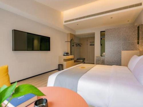 a hotel room with a large white bed and a tv at Airfeel Hotel in Ziyang