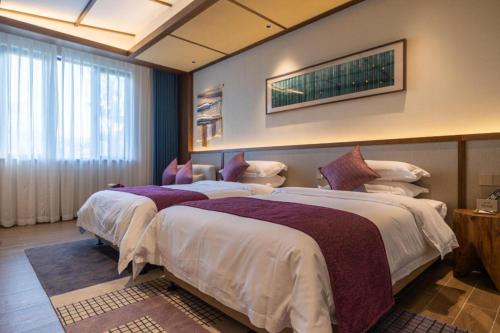 a hotel room with two beds in a room at Wuyuan Wunvzhou Wuxiandao Luxury Hotel in Wuyuan
