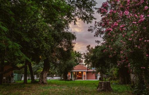 a house in a yard with trees and pink flowers at Thea simply by the sea in Preveza