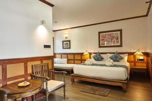 a bedroom with a bed and a table and chairs at My BanLao Hotel in Luang Prabang