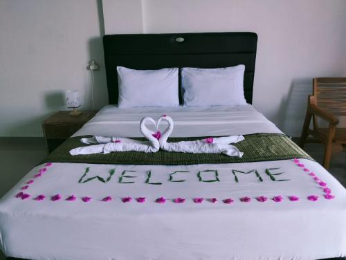 a bed with a welcome sign and flowers on it at Arirang Sea View Homestay in Senggigi 