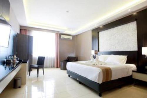 a hotel room with a large bed and a desk at Karlita Hotel Tegal in Tegal