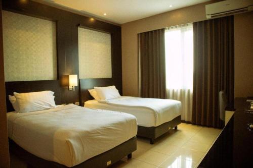 a hotel room with two beds and a window at Karlita Hotel Tegal in Tegal