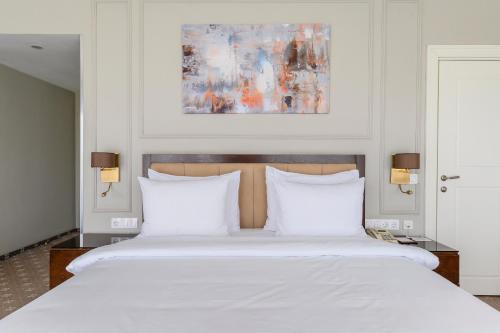 a bedroom with a large white bed with white pillows at Almaty Hotel in Almaty
