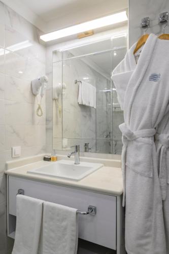 a white bathroom with a sink and a mirror at Almaty Hotel in Almaty