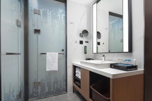 a bathroom with a sink and a shower with a mirror at 北京传媒大学希尔顿欢朋酒店Hampton by Hilton Beijing Communication University in Beijing