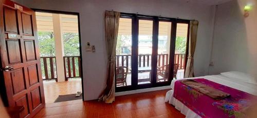 une chambre avec un lit et une porte donnant sur un balcon dans l'établissement Saikaew Villa, à Ko Samet