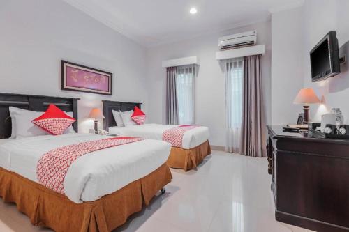 a hotel room with two beds and a flat screen tv at Sriwijaya Hotel in Jakarta