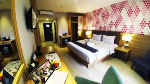 a hotel room with a bed and a couch at Orchardz Hotel Gajah Mada in Pontianak