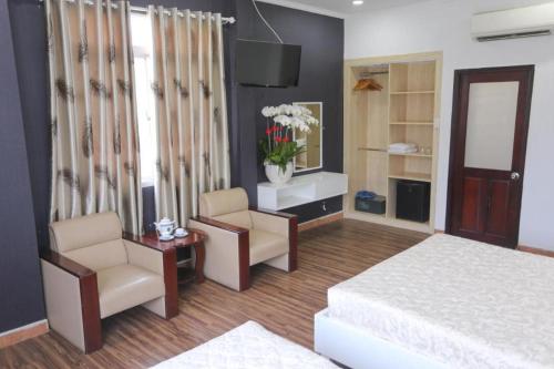 a bedroom with a bed and two chairs and a mirror at Rain Bow Hotel in Ho Chi Minh City