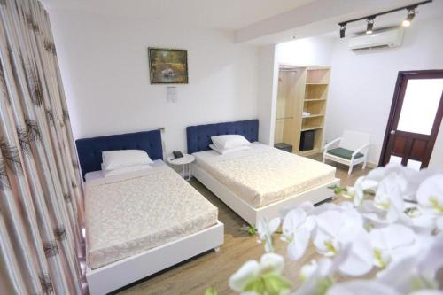 two beds in a room with white walls and flowers at Rain Bow Hotel in Ho Chi Minh City