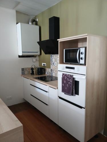 une cuisine avec une cuisinière blanche et un micro-ondes dans l'établissement La Parenthèse Comtoise, à Dole