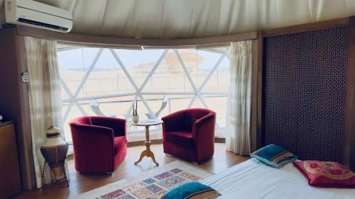 a bedroom with two chairs and a large window at Star Wars luxury camp in Wadi Rum
