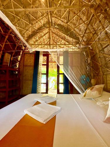 a bedroom with a large white bed with a roof at Dosplaya Ecocamp in El Nido