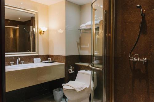 a bathroom with a toilet and a sink and a shower at Aramis Hotel in Nakhon Sawan