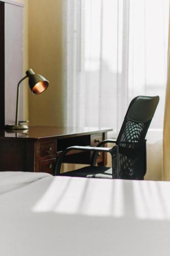 a bedroom with a desk and a chair and a lamp at Aramis Hotel in Nakhon Sawan