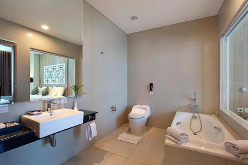 a bathroom with a tub and a sink and a toilet at Golden Tulip Galaxy Hotel Banjarmasin in Benuaanyar